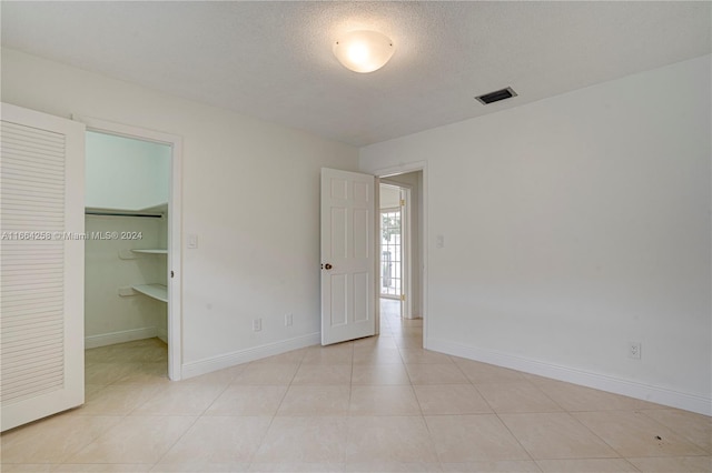 unfurnished bedroom with a closet, a spacious closet, and light tile patterned floors