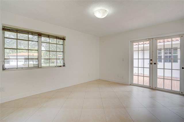 tiled spare room with french doors and a textured ceiling