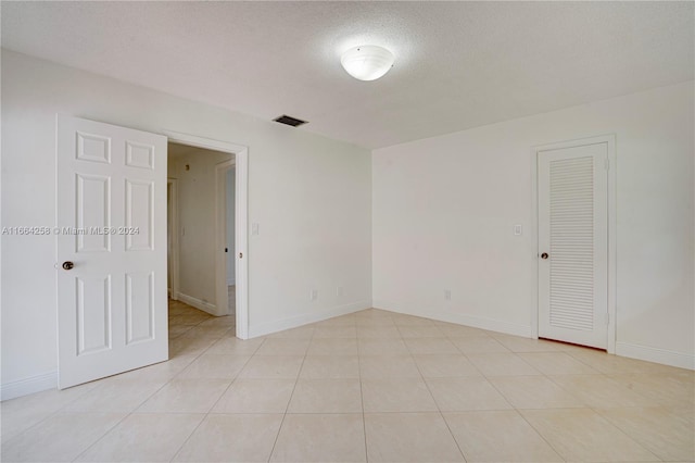 empty room with a textured ceiling and light tile patterned floors