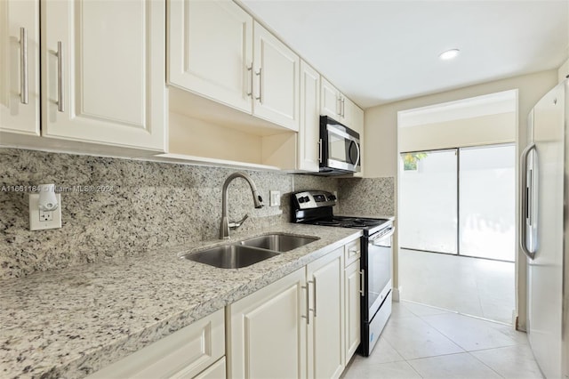 kitchen featuring stainless steel appliances, white cabinetry, light stone countertops, decorative backsplash, and sink