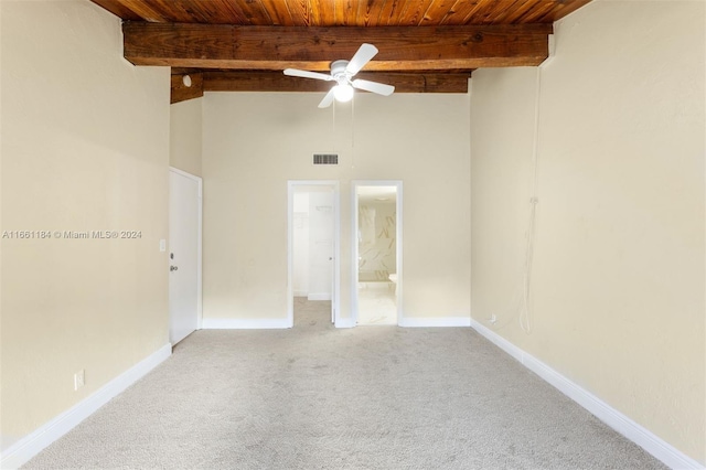 carpeted empty room with a towering ceiling, beam ceiling, ceiling fan, and wood ceiling