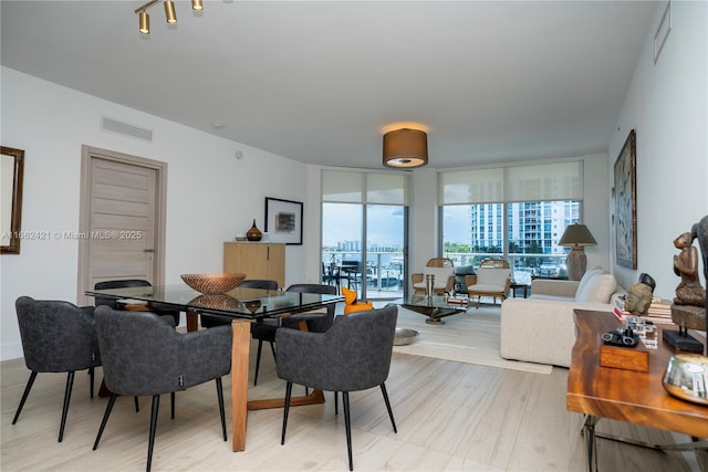 dining space with light wood-type flooring, expansive windows, and visible vents