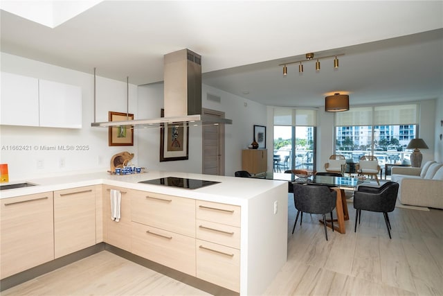 kitchen with black electric stovetop, open floor plan, light brown cabinets, island range hood, and modern cabinets