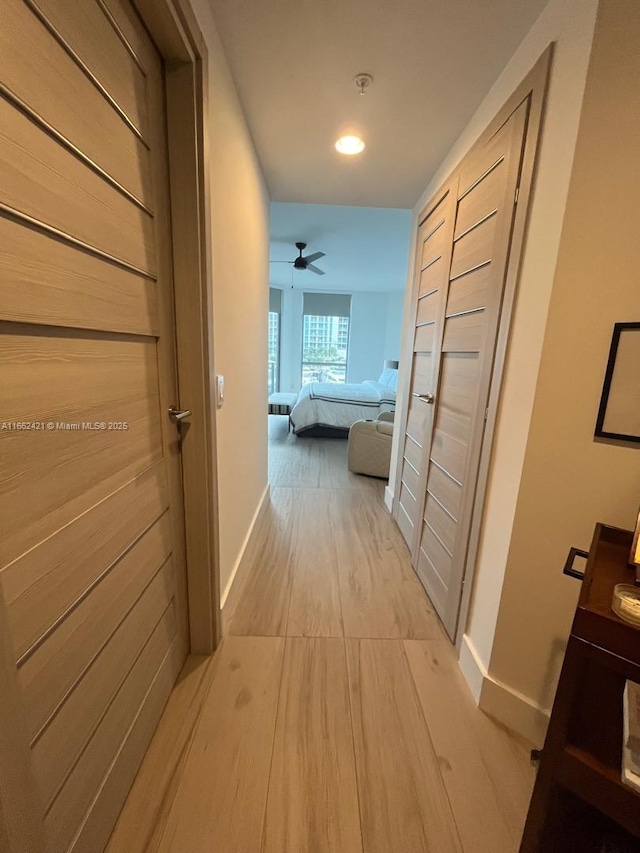 corridor featuring light wood-type flooring and baseboards