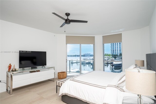 bedroom with light hardwood / wood-style flooring, ceiling fan, and a wall of windows