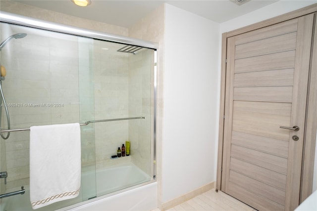 bathroom with bath / shower combo with glass door and tile patterned flooring