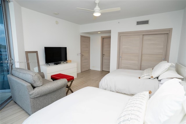 bedroom with light wood finished floors, visible vents, and a ceiling fan