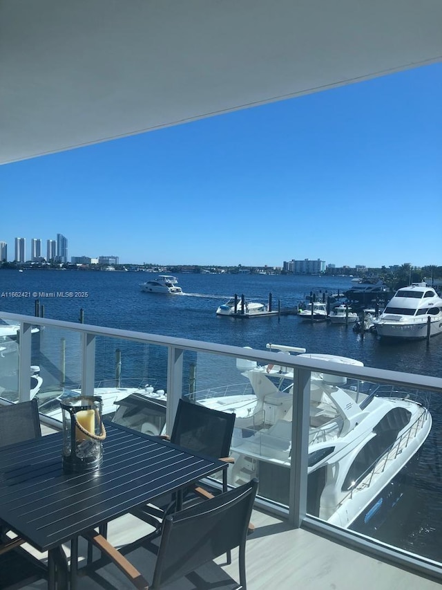 balcony featuring outdoor dining space, a water view, and a city view