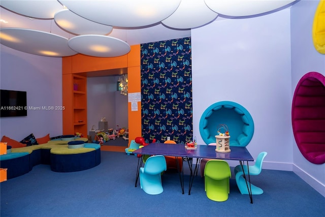 recreation room with carpet floors, built in shelves, and baseboards