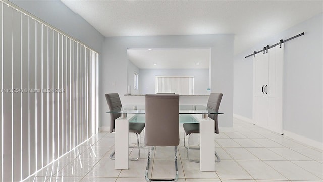 tiled dining space featuring a textured ceiling and a barn door