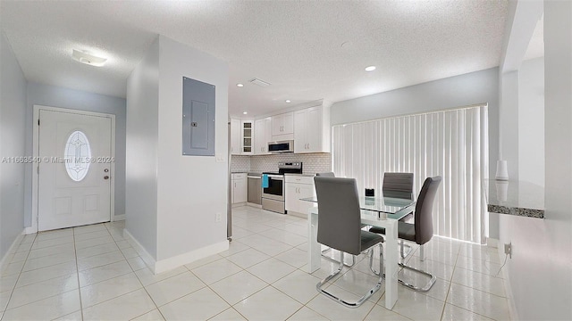 tiled dining room featuring a textured ceiling and electric panel