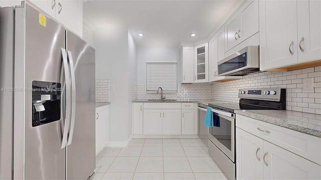 kitchen with stainless steel appliances, white cabinets, light tile patterned flooring, and sink