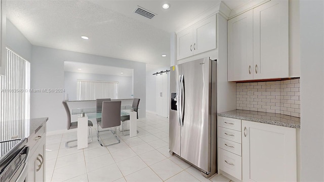 kitchen featuring light stone counters, white cabinets, tasteful backsplash, a textured ceiling, and stainless steel fridge with ice dispenser