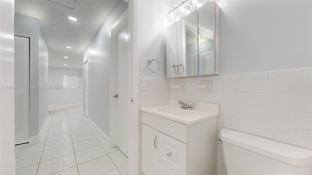 bathroom featuring tile walls, tile patterned flooring, a textured ceiling, vanity, and toilet