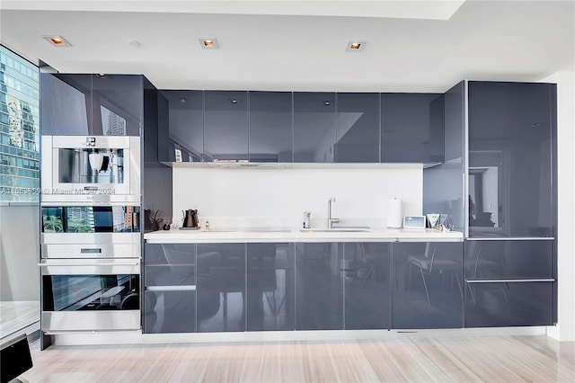 kitchen featuring light wood-type flooring, sink, and stainless steel double oven