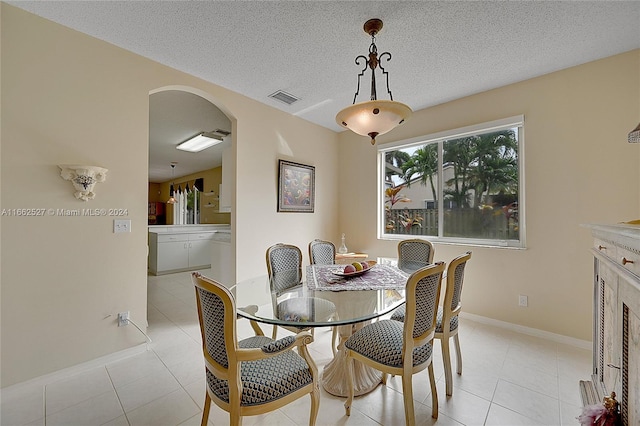 dining area featuring a textured ceiling and light tile patterned floors