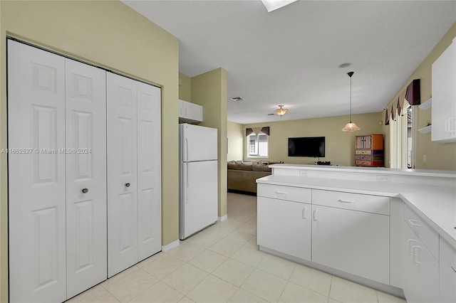 kitchen with white cabinets, light tile patterned flooring, hanging light fixtures, and white fridge