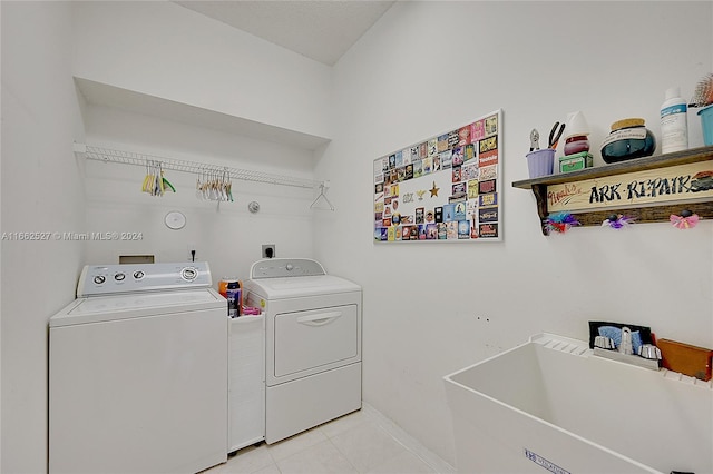 laundry area featuring washer and clothes dryer, sink, and light tile patterned floors