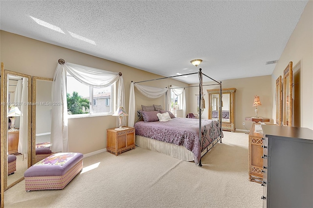 bedroom with a textured ceiling and light colored carpet