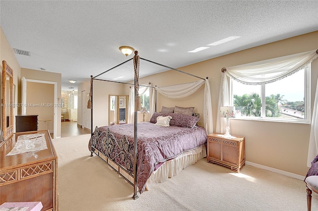 carpeted bedroom featuring a textured ceiling and ensuite bathroom