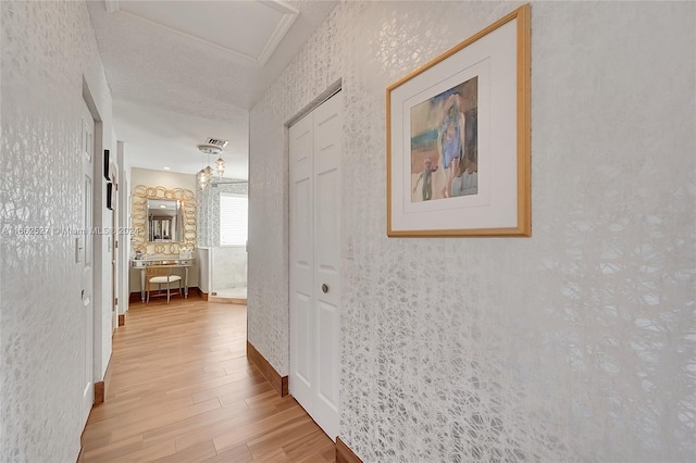 hallway with light hardwood / wood-style flooring and a textured ceiling