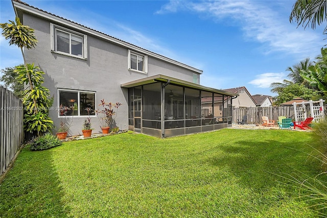 rear view of house featuring a sunroom and a yard