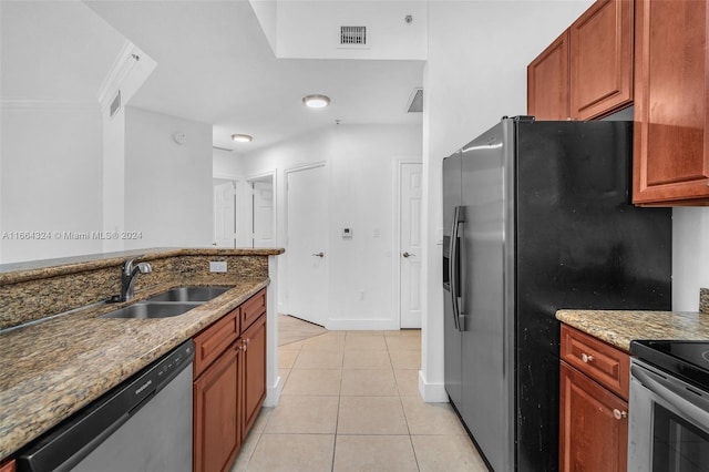 kitchen with light stone counters, light tile patterned floors, sink, and stainless steel dishwasher