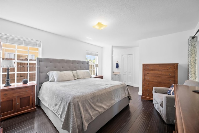 bedroom with ensuite bathroom, a closet, dark hardwood / wood-style flooring, and a textured ceiling