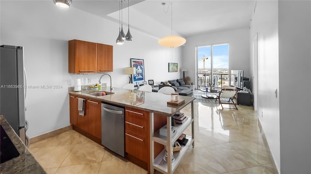 kitchen featuring kitchen peninsula, stone countertops, stainless steel appliances, decorative light fixtures, and sink