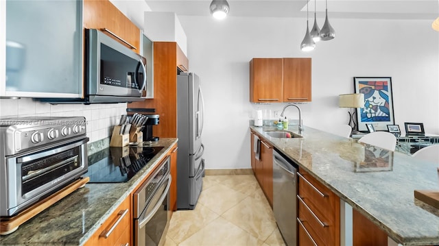 kitchen with appliances with stainless steel finishes, tasteful backsplash, stone countertops, pendant lighting, and sink