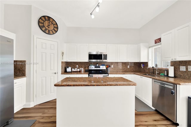 kitchen featuring a center island, stainless steel appliances, wood-type flooring, decorative backsplash, and white cabinets