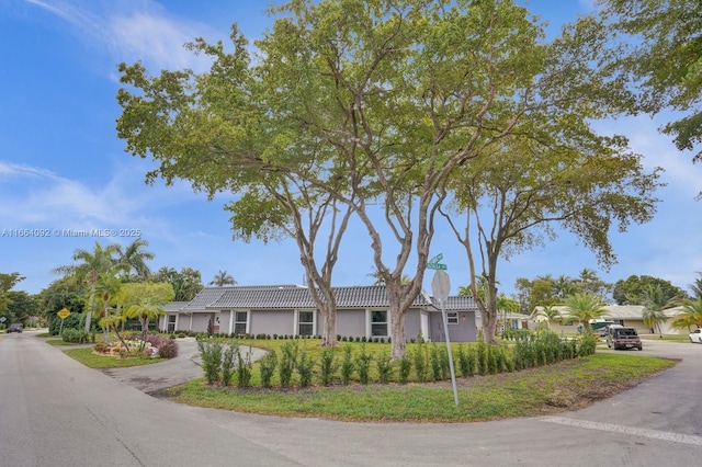 ranch-style home with stucco siding, driveway, and a tile roof