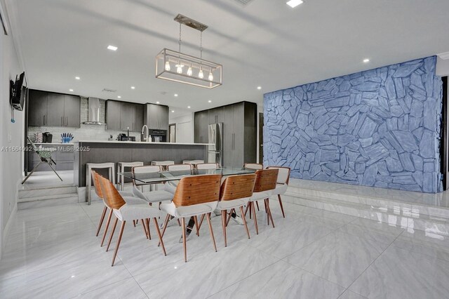 kitchen featuring a kitchen island with sink, tasteful backsplash, wall chimney range hood, a kitchen breakfast bar, and black appliances