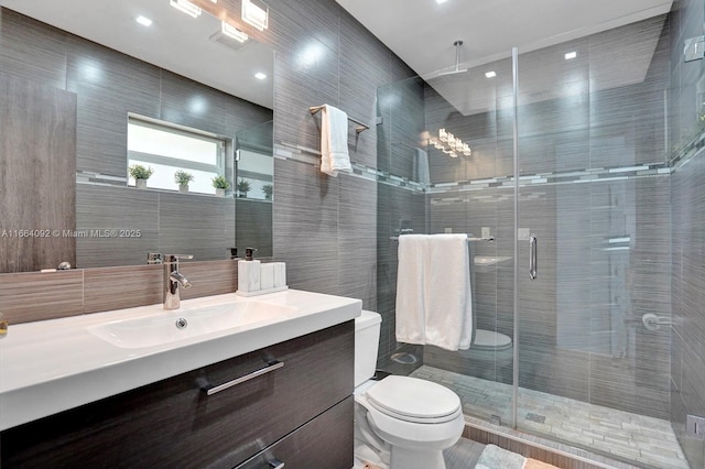 full bathroom with a shower stall, vanity, toilet, and tile walls