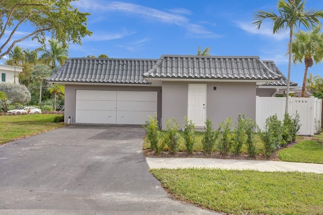 view of front of property featuring a tiled roof, fence, driveway, and stucco siding