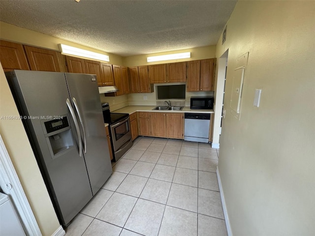 kitchen with stainless steel appliances, a textured ceiling, and light tile patterned flooring