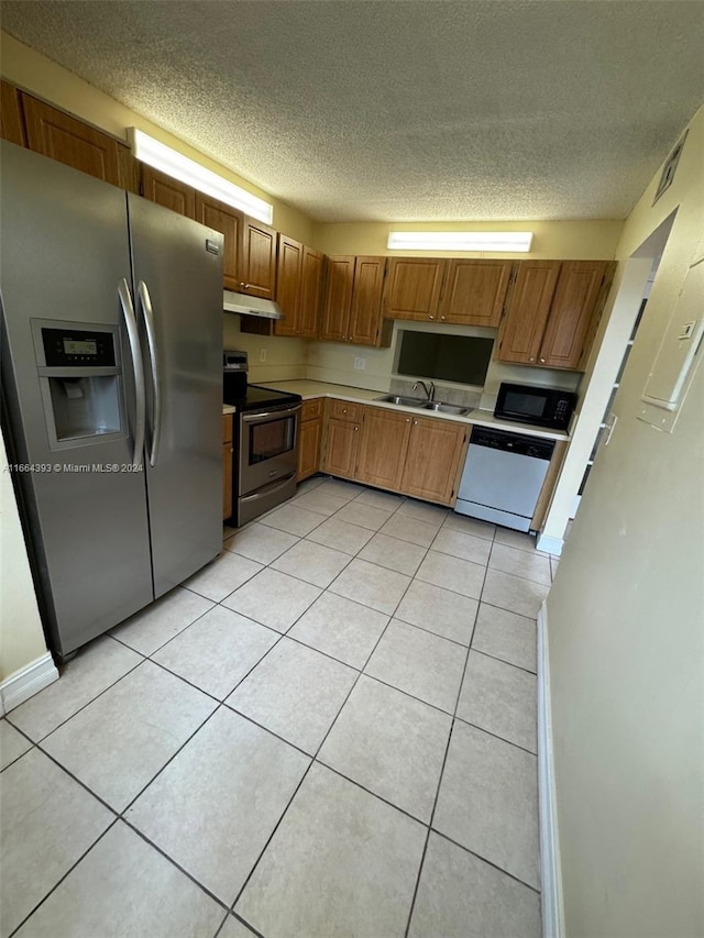 kitchen featuring stainless steel appliances, a textured ceiling, light tile patterned floors, and sink