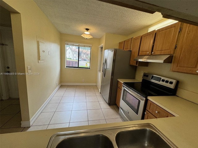 kitchen with light tile patterned flooring, stainless steel appliances, and a textured ceiling