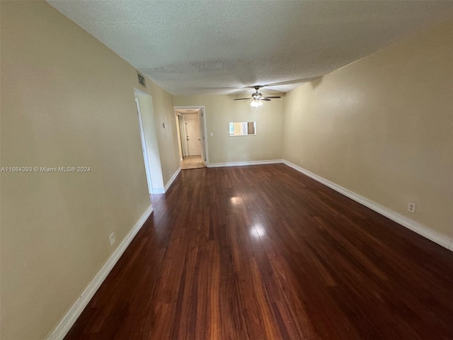 spare room with a textured ceiling, ceiling fan, and dark hardwood / wood-style flooring