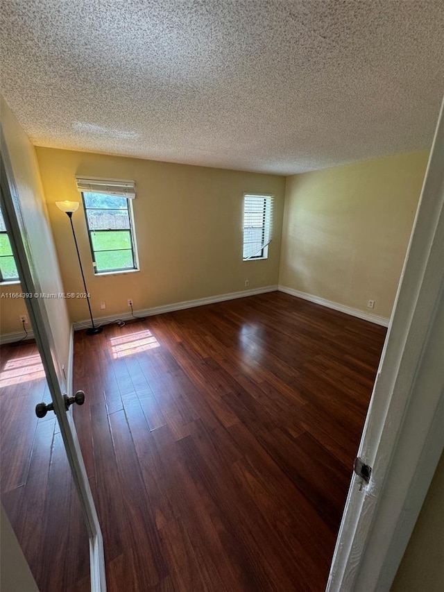 spare room with a textured ceiling and dark wood-type flooring