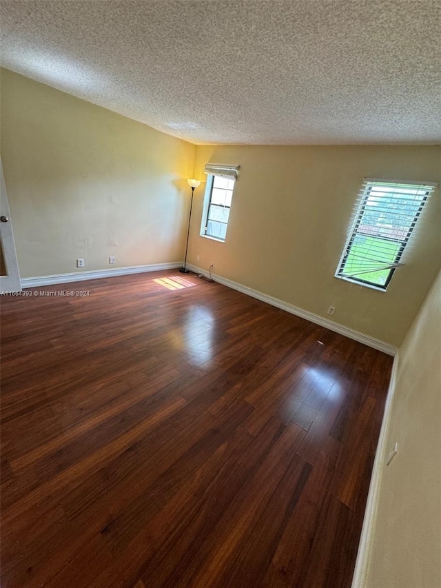 spare room with a textured ceiling and dark hardwood / wood-style floors