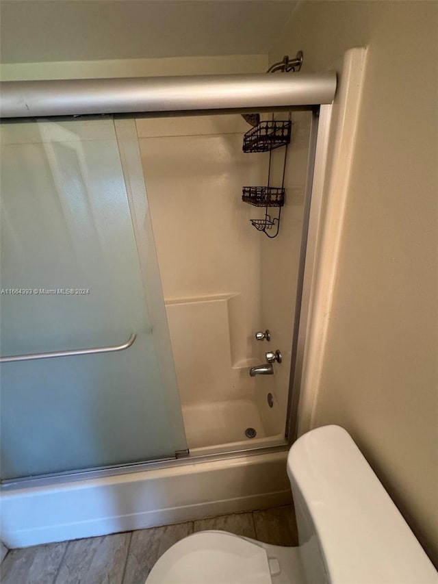 bathroom with bath / shower combo with glass door and toilet