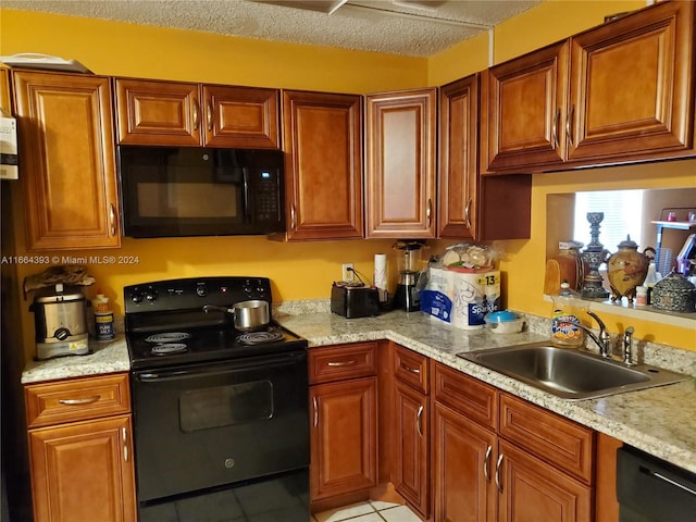 kitchen with light tile patterned flooring, light stone counters, a textured ceiling, black appliances, and sink