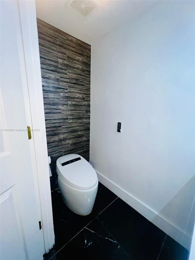 bathroom with tile walls and toilet