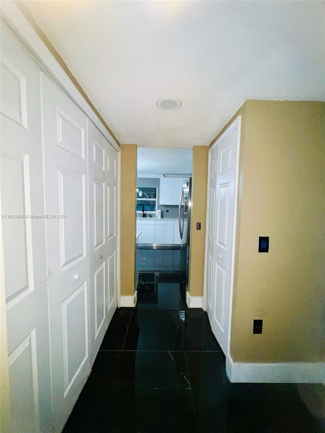 hall featuring dark tile patterned flooring