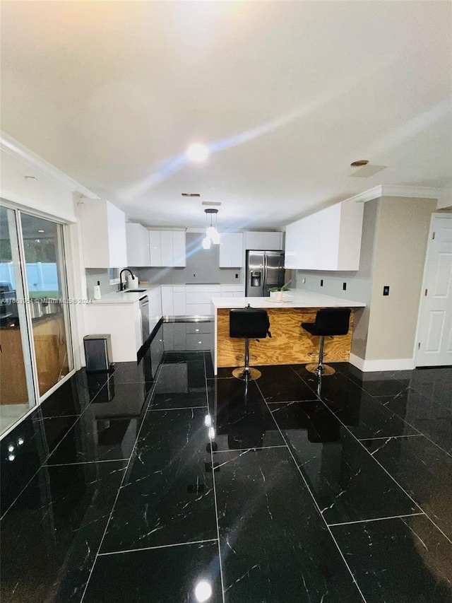 kitchen featuring a breakfast bar, white cabinets, stainless steel appliances, crown molding, and sink