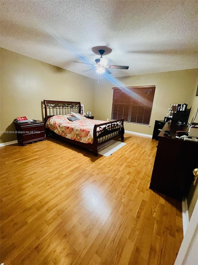 bedroom with a textured ceiling, wood-type flooring, and ceiling fan