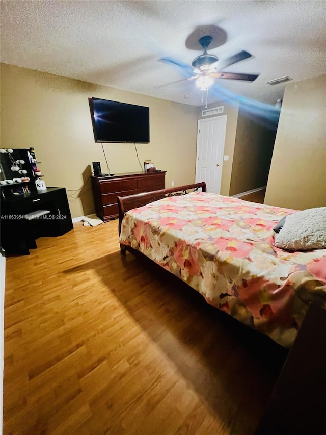 bedroom featuring a textured ceiling, hardwood / wood-style floors, and ceiling fan