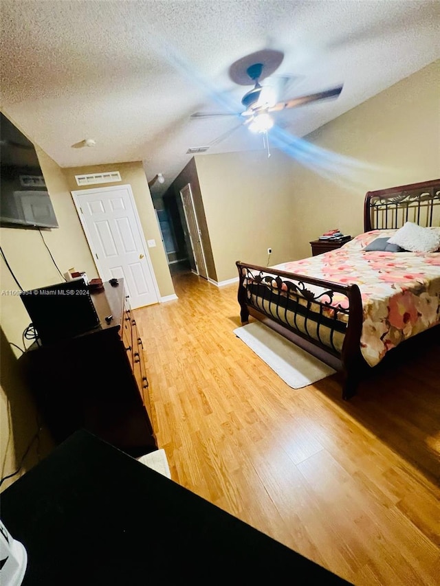 bedroom featuring ceiling fan, hardwood / wood-style floors, and a textured ceiling