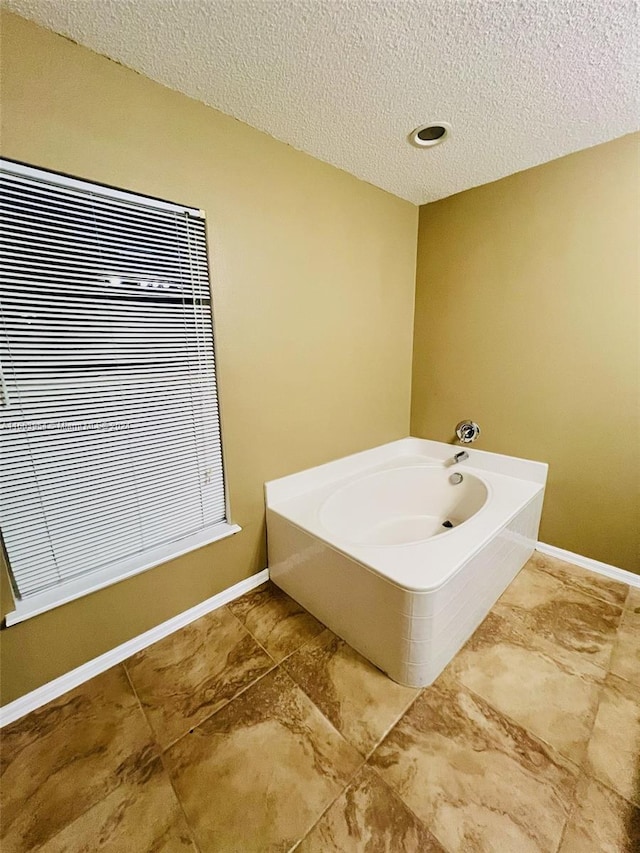 bathroom featuring a textured ceiling and a bathing tub